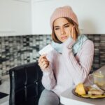 Unhealthy young woman holding pill at hands while have a flu.