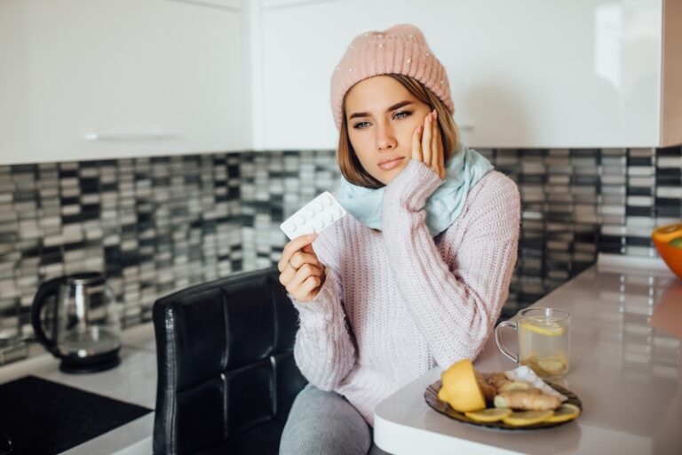 Unhealthy young woman holding pill at hands while have a flu.