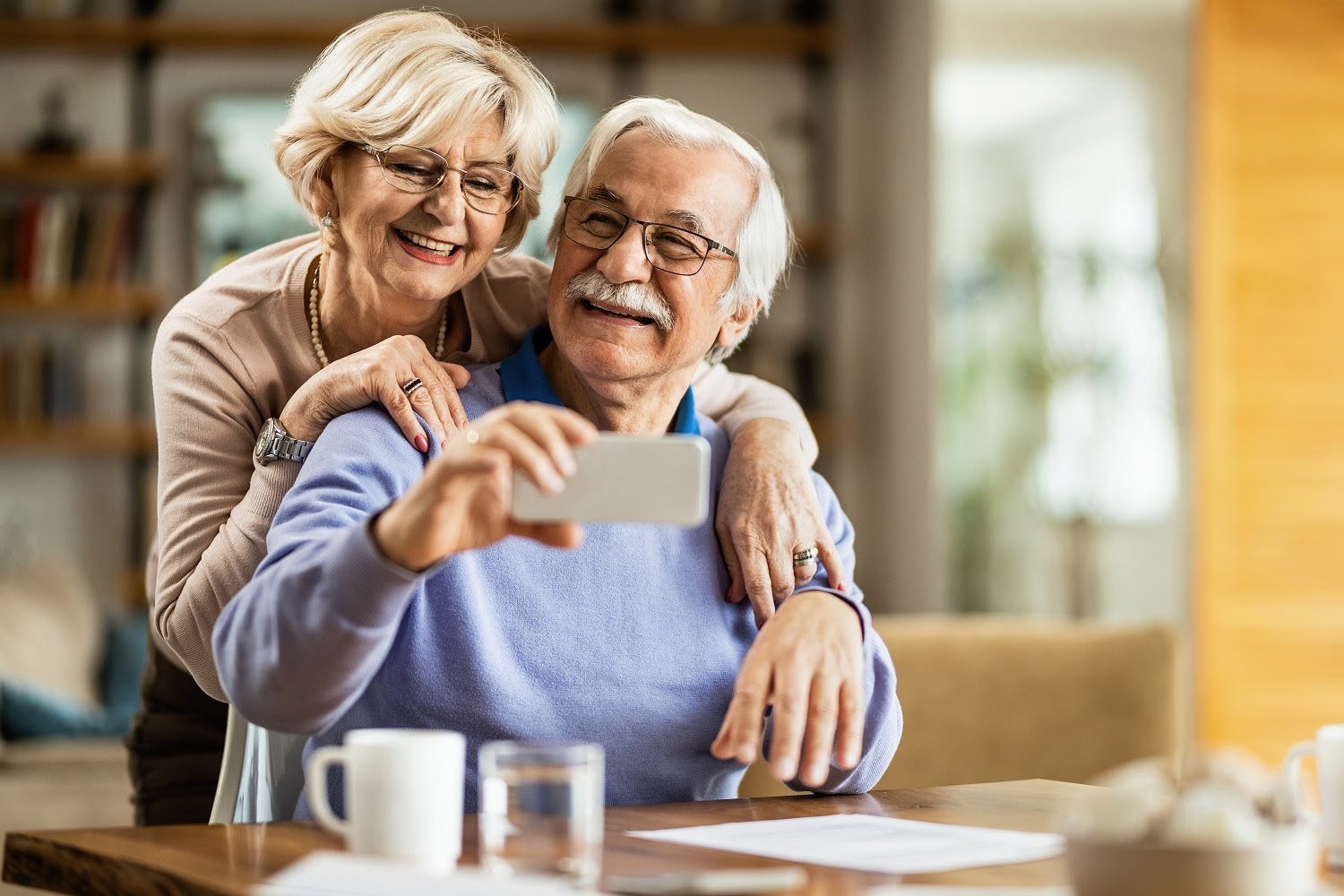 Happy mature couple using mobile phone and having fun while taking selfie.