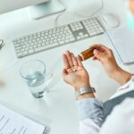 Close-up of businesswoman taking medicine in the office.