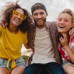 happy young company of smiling friends excited in park, man and women having fun together, colorful summer hipster fashion style, smiling