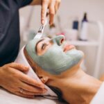 cosmetologist-applying-mask-face-client-beauty-salon